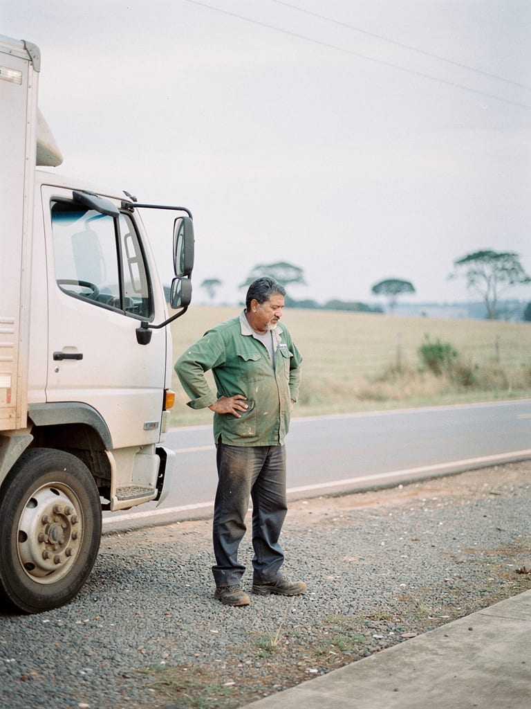 A truck driver stretching beside his parked truck at dawn before a long haul